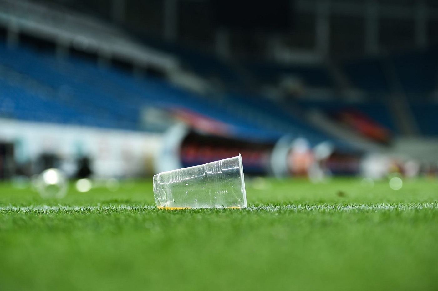 Vaso de plástico desechado sobre el pasto de una cancha